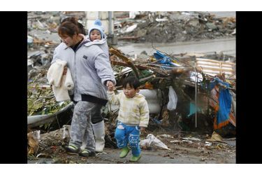 Un famille marche entre les décombres de la ville de Minamisanriku, située dans la préfecture de Miyagi, au nord du Japon.