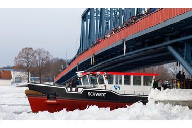 Des passants regardent un Brise-glace sur la rivière Oder à Schwedt, à la frontière de la Pologne. Le niveau du cours d’eau est critique, les températures s’étant radoucies dans la région.