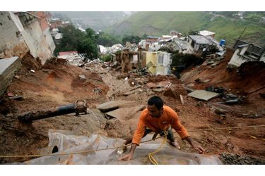 Un habitant de Caracas (Venezuela) tente d’empêcher les infiltrations d’eau en recouvrant de plastique la terre, après un glissement de terrain dans le quartier d’Altavista.