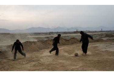 Des ouvriers d'une briqueterie, près de Kaboul, en Afghanistan, se détendent avec une partie de football pendant leur pause.