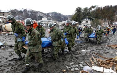 Des militaires japonais transportent les corps des victimes du tsunami à Yamadamachi, au nord du Japon.