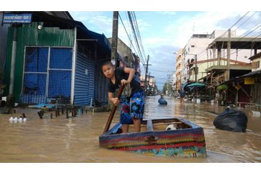 Un garçon utilise un radeau de fortune pour circuler à travers les rues inondées de Had Yai, dans la province de Songkhla, en Thaïlande.