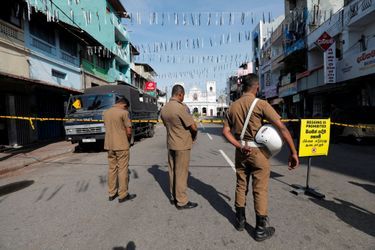 Des membres des forces de sécurités se recueillent durant trois minutes de silence, près de l'église Saint-Antoine, à Colombo, mardi.
