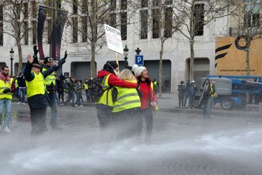 Des «gilets jaunes» font face aux jets d&#039;eau, samedi sur les Champs-Elysées.