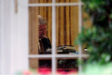 Bill Clinton, cigare à bouche, dans le bureau ovale de la Maison Blanche, le 31 juillet 1998. Trois jours avant, le 28 juillet, Monica Lewinsky, obligée de reconnaitre sa relation avec Clinton face au procureur Kenneth Starr, avait passé un accord provisoire avec lui afin de bénéficier d&#039;un statut d&#039;immunité, en échange de révélations sur ses relations avec le président américain.