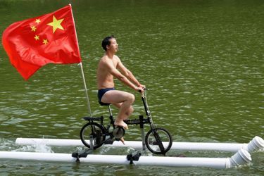 Liu Wanyong sur son vélo flottant sur deux tuyaux