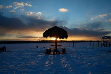 A thatched roundtable sits on a snow-covered beachfront in Port Washington, New York
