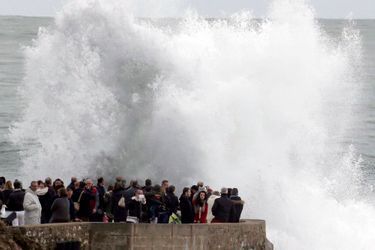People look at waves breaking on a beach front at high tide in Biarritz