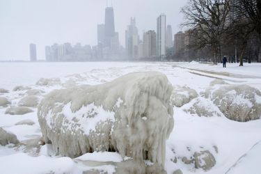A woman walks along a path past mounds of snow and ice along Lake Michigan in Chicago