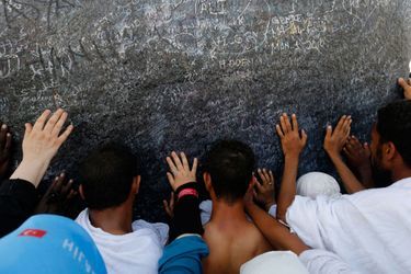 Des pèlerins touchent une pierre au sommet du Mont Arafat