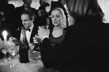 Catherine DENEUVE souriante (Meilleure actrice pour &quot;Le dernier métro&quot;), assise entre François TRUFFAUT (Meilleur réalisateur et meilleur film) et Gérard DEPARDIEU (Meilleur acteur), tous trois à table un verre àla main au dîner donné au Fouquet&#039;s à PARIS.