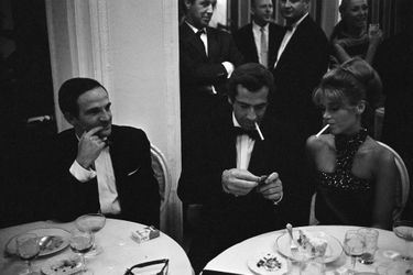 Mostra de Venise 1966 : venus présenter leur film "La Curée" au festival, Roger VADIM et son épouse Jane FONDA dînant à une table, cigarette à la bouche, François TRUFFAUT, venu promouvoir son film "Fahrenheit 451", assis à leur côté.