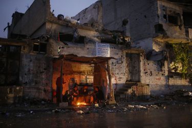 Des Palestiniens se réchauffent avec un feu, à Gaza