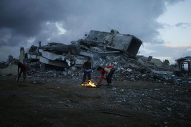 Deux garçons allument un feu pour éclaire une zone dévastée à Gaza