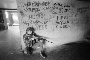 Septembre 1979, en IRLANDE du NORD, à BELFAST, le déploiement de l&#039;armée anglaise dans la ville : soldat armé en position de tir dans un couloir d&#039;immeuble d&#039;habitation aux murs graffités.