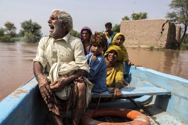 Une famille évacue sa maison noyée sous les eaux dans une barque, à Jhang, au Pakistan