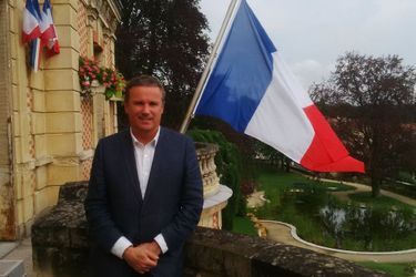 Nicolas Dupont-Aignan, député de l&#039;Essonne et président de Debout la République, pose devant le drapeau de sa mairie de Yerres.
