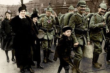 A Berlin, les soldats allemands, boutonnière fleurie, portent encore le casque à pointe qu’ils abandonneront en 1916. A leurs femmes et leurs enfants, ils disent : « Nous serons bientôt là. »