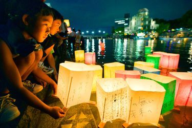 Des enfants déposent des lanternes de papiers dans la rivière Motoyasu en souvenir des victimes