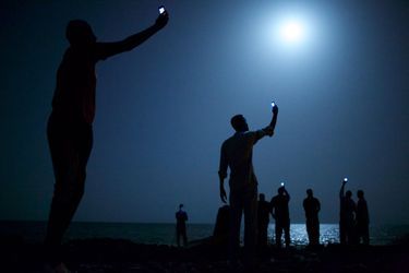 <br />
John Stanmeyer, USA, VII for National Geographic  <br />
26 février 2013, Djibouti City, DjiboutiLes migrants tentent de capter avec leurs téléphones portables un signal ténu de leurs proches restés en Somalie, leur pays d&#039;origine de l&#039;autre côté de la baie.
