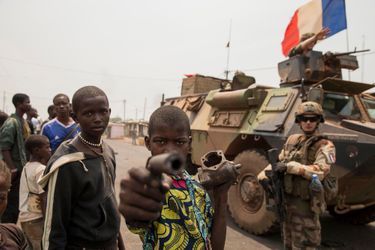 En mars 2013, la prise du pouvoir à Bangui par les milices musulmanes du Seleka s’est accompagnée d’un cortège de 2 000 morts et d’un million de déplacés. Un an plus tard, les ex-victimes se sont muées en bourreaux. Pour les anti-balaka chrétiens, la soif de vengeance semble inextinguible. Ni la présidente, Catherine Samba-Panza, ni les 1 600 soldats de l’opération Sangaris, ne calment le jeu. Le 15 février, Jean-Yves Le Drian, le ministre de la Défense, a annoncé un renfort de 400 hommes, précisant que « ça sera plus long que prévu parce que le niveau de haine et de violence est plus important qu’on imaginait ».Ci-dessus: Lundi 17 février, des gamins des rues jouent aux guerriers autour d’un véhicule blindé de l’opération Sangaris.