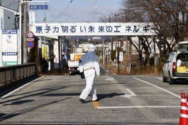 Mardi, un travailleur de décontamination passe devant une pancarte: &quot;L&#039;énergie nucléaire - L&#039;énergie pour un avenir meilleur&quot; à l&#039;entrée de la ville déserte de Futaba, non loin de la centrale nucléaire.