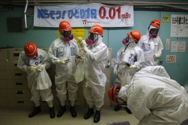 Des membres des médias accompagnés d&#039;employés de Tokyo Electric Power Co. sont entrés lundi dans la centrale nucléaire de Fukushima. Ils se tiennent près d&#039;une banderole où l&#039;on peut lire: &quot;Diminution de 0,01 mSv par jour pour une personne&quot;.