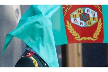 Un garde se retrouve le visage caché par le drapeau national du Turkménistan à l’occasion de l’arrivée du président Gurbanguly Berdimuhamedow à Kiev, en Ukraine.