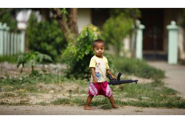 Un jeune garçon joue avec une arme factice près de sa maison de Rangoun en Birmanie.