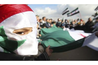 Le visage camouflé par un drapeau découpé, un Syrien manifeste contre le régime de Bashar Al-Assad devant l’ambassade d’Amman.  