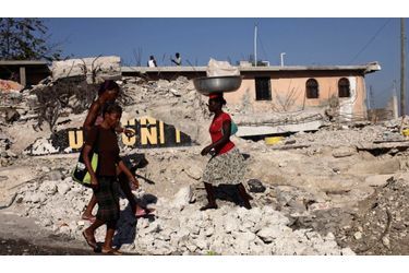 Des Haïtiens marchent entre les débris causés par le séisme à Port-au-Prince.