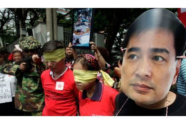 Lors d’une manifestation des &quot;chemises rouges&quot; antigouvernementales, un homme porte un masque du Premier ministre Abhisit Vejjajiva, tandis que d’autres se moquent de la rigueur des autorités Thaïlandaises. Mardi, le procureur général a annoncé la dissolution du parti démocrate. Une décision qui pourrait faire bannir le Premier ministre de la vie politique pour une durée de cinq ans.