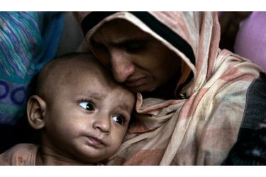 L&#039;épouse en larmes et le petit garçon d&#039;un pakistanais, tué dans la nuit du 2 juillet 2010 par une attaque-suicide à la bombe, pleurent à côté de son corps exposé dans leur maison familiale de Lahore.