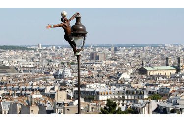 Surplombant la capitale du haut de Montmartre, le footballeur guinéen Iya Traore escalade un lampadaire tout en jonglant avec un ballon dans les jardins de la basilique du Sacré Coeur, sous le soleil dominical du 4 juillet 2010.