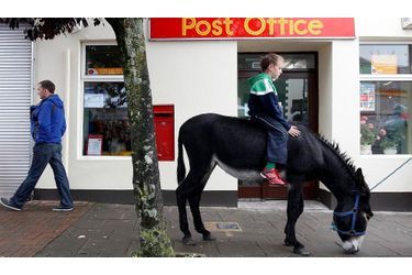 Cet enfant, assis sur un âne, attend devant le bureau de poste la fin de la vente d&#039;ânes organisée à Irvinestown, en Irlande du Nord.