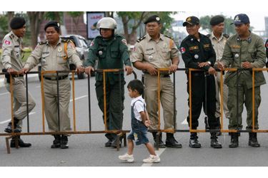 Les policiers cambodgiens regardent un petit enfant passer devant eux lors de la commémoration de la mort de Chea Vichea, un leader syndicaliste du pays assassiné il y a cinq ans.