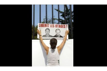 Une femme accroche une affiche sur les grilles du Jardin du Luxembourg, à Paris. Une manifestation était organisée aujourd'hui en honneur aux deux journalistes de France Télévisions, Stéphane Taponier et Hervé Ghesquiere, otages en Afghanistan depuis le 29 décembre 2009.