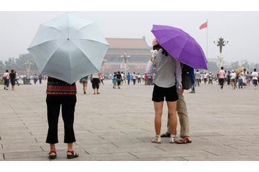 <br />
Des touristes visitent la place Tian&#039;anmen, à Pékin, en se protégeant du soleil avec des parapluies. 