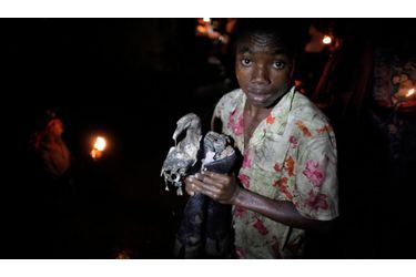 Un enfant tient dans ses mains des pieds de vache, après que l&#039;animal ait été sacrifié lors d’un rituel de masse au cours du festival Plain Du Nord (Haiti). Des milliers de croyants sacrifient ainsi des animaux et prient dans des piscines de boue afin de demander aux esprits vaudous et aux morts de les aider financièrement, dans le futur et de protéger les enfants.