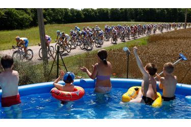 Des enfants applaudissent les cyclistes du Tour de France alors qu&#039;ils font trempette dans une piscine.