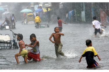 Les enfants jouent dans une rue inondée, causée par de lourdes pluies apportées par la tempête tropicale Maring, dans la ville Malabon, au nord de Manille.