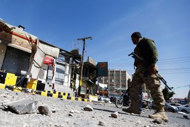 Un combattant chiite devant un magasin ravagé à côté du palais présidentiel de Sanaa