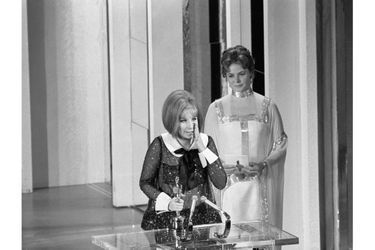 41ème cérémonie des Oscars (1969)Surprise inédite : en ouvrant l'enveloppe, Ingrid Bergman n'a pu cacher sa stupéfaction... Deux comédiennes remportent ex-aequo l'Oscar de la meilleure actrice. Katharine Hepburn pour "Le lion en hiver" et Barbra Streisand pour "Funny Girl". Seule la deuxième montera sur scène pour faire un discours, Katharine Hepburn étant absente (comme à chaque cérémonie des Oscars). (Photo : Barbra Streisand fait son discours de remerciements sous les yeux d'Ingrid Bergman)