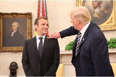 24 avril 2018. Dans le Bureau Ovale, Donald Trump fait mine d'enlever quelques pellicules sur l'épaule d'Emmanuel Macron. 