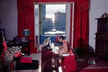 Charles Aznavour joue du piano dans sa maison de Saint-Tropez en juin 1964.