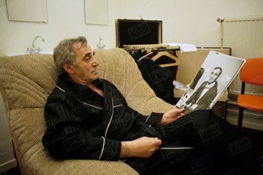 Charles Aznavour dans sa loge à l&#039;occasion d&#039;un concert à Dunkerque, regardant une photographie de lui-même, le 10 décembre 1987.