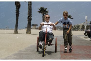 Charles Aznavour fait du tricycle sur la promenade de Santa Monica, en Californie, au bord de la plage, avec son fils Nicolas (11 ans) l&#039;accompagnant en patins à roulettes, le 7 juillet 1987.