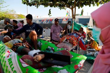 Des villageois blessés sont allongés sur des lits à l'extérieur de l'hôpital de Tanjung.