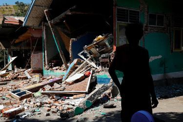Un villageois se tient devant une salle de classe endommagée par le séisme à Pemenang.