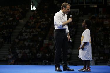 Emmanuel Macron parle avec un jeune garçon sur scène lors d'un meeting à Saint Denis, à la Réunion.